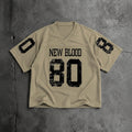 A beige short-sleeve football-style jersey laid flat on a textured gray surface, with distressed black text reading 'NEW BLOOD' and large '80' on the front, plus black '0' and '8' graphics on the sleeves.